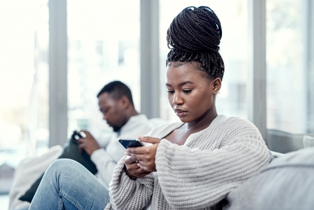 couple using their smartphones on the sofa at home