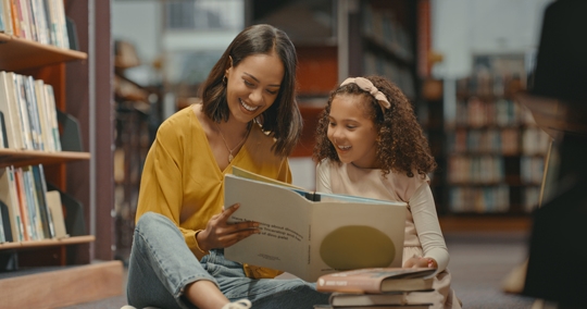 mother and daughter reading a book in the library
