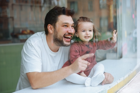 father and daughter laughing and looking out the window