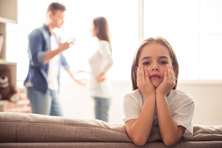 sad child with parents fighting in the background
